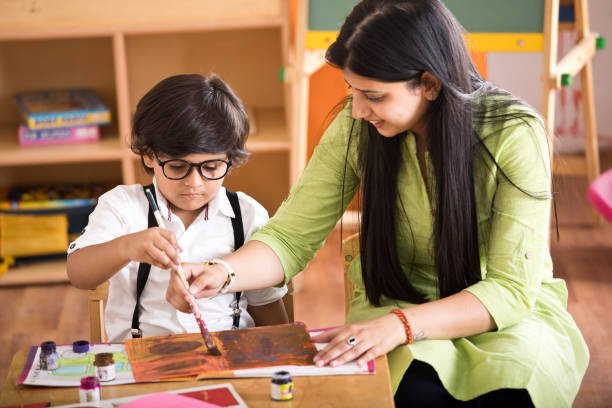 preschool children doing painting with teacher in art class
